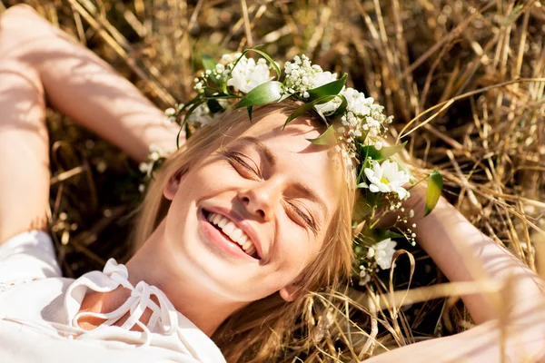 Mujer feliz en corona de flores acostada sobre paja — Foto de Stock