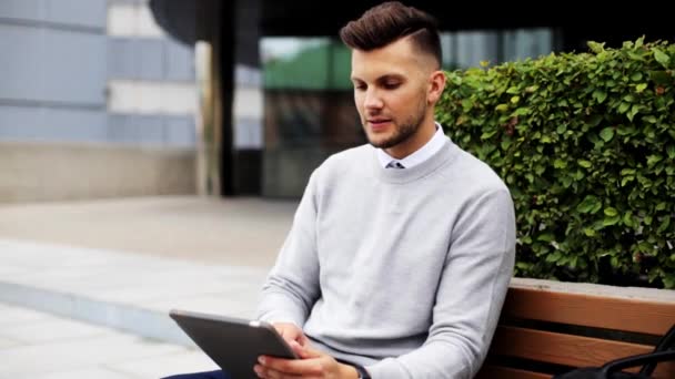 Man with tablet pc sitting on city street bench — Stock Video