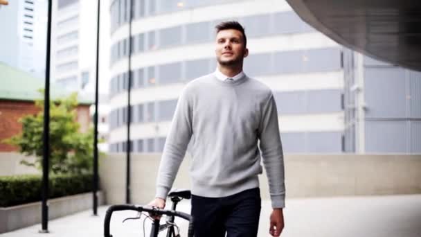 Młody człowiek spaceru wzdłuż miasta ulica z rowerem — Wideo stockowe