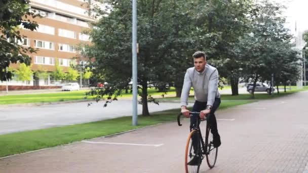 Молодой человек на велосипеде по улице города — стоковое видео