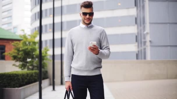 Jeune homme avec des lunettes de soleil et sac de marche en ville — Video