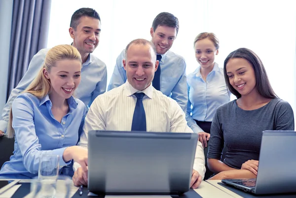 Uśmiechnięci biznesmeni z laptopem w biurze — Zdjęcie stockowe