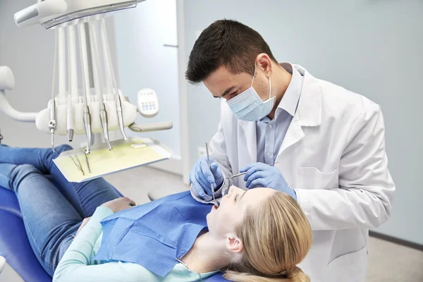 Dentista masculino em máscara verificando os dentes do paciente feminino — Fotografia de Stock