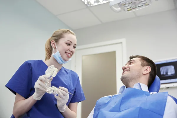 Happy dentist showing jaw layout to male patient — Stock Photo, Image