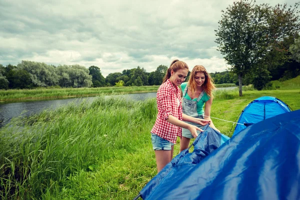 Amigos sonrientes instalando carpa al aire libre —  Fotos de Stock