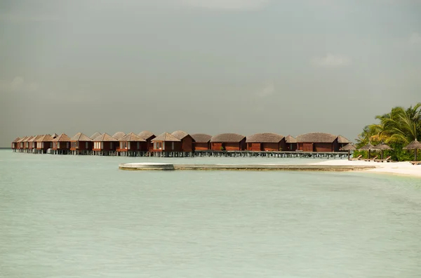 Bungalow huts i havsvatten på exotiska resort beach — Stockfoto