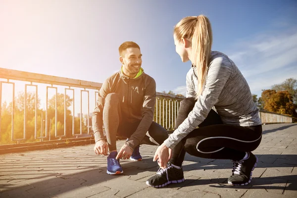 Coppia sorridente allacciatura lacci delle scarpe all'aperto — Foto Stock