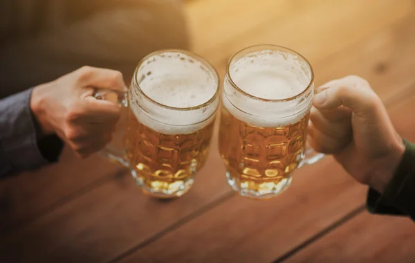 Close up of hands with beer mugs at bar or pub — Stock Photo, Image