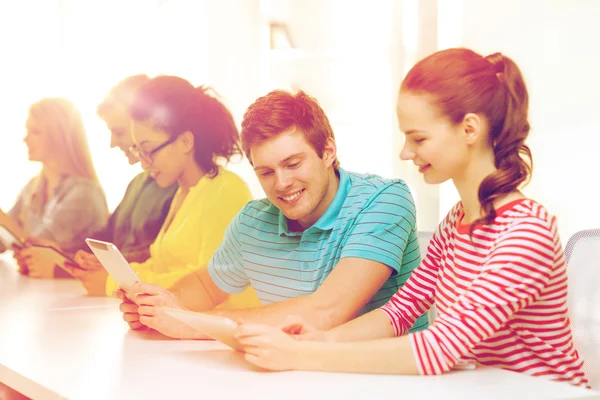 Lachende studenten kijken naar tablet pc op school — Stockfoto