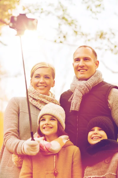 Happy family with smartphone and monopod in park — Stock Photo, Image