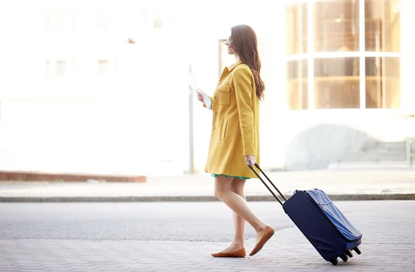 Happy young woman with travel bag and map in city — Stock Photo, Image