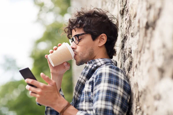 Man with smartphone drinking coffee on city street — Stock Photo, Image