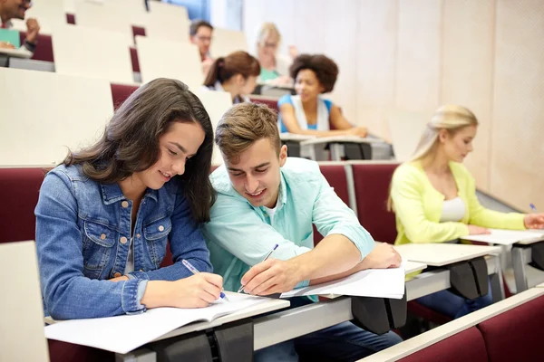 Grupp studenter med anteckningsböcker i föreläsningssalen — Stockfoto