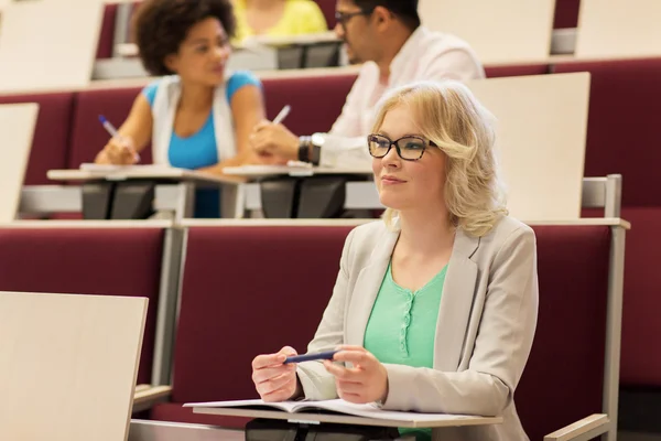 Student girl writing to notebook in lecture hall — Stock Photo, Image