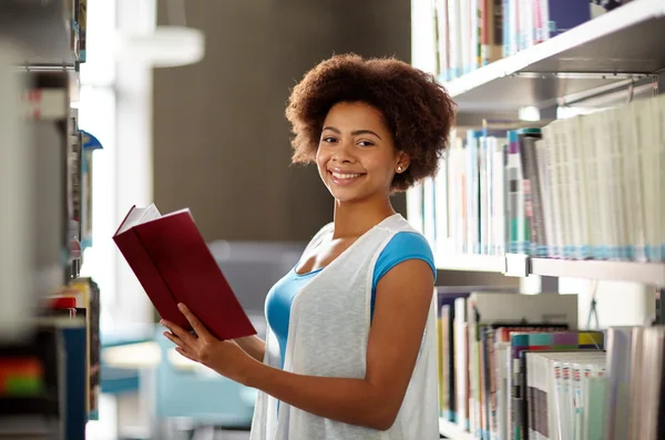 Gelukkig Afrikaanse student meisje leesboek bij bibliotheek — Stockfoto