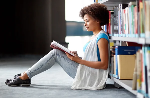 Afrikanska student tjej läsa bok på biblioteket — Stockfoto