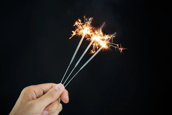 Hand vasthouden van wonderkaarsen over zwarte achtergrond — Stockfoto