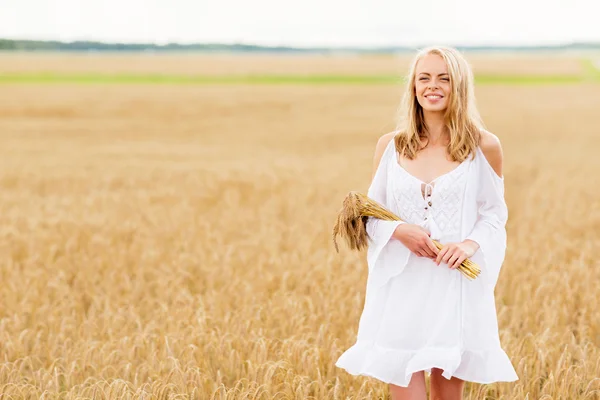 Heureuse jeune femme avec des épillets sur le champ de céréales — Photo