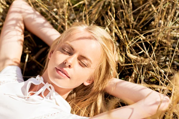 Gelukkig jonge vrouw liggend op granen veld of hooi — Stockfoto
