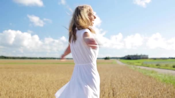 Lächelnde junge Frau im weißen Kleid auf einem Getreidefeld — Stockvideo