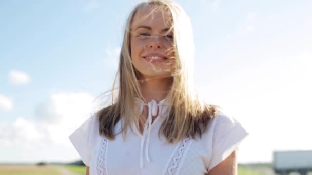 Усміхнена молода жінка в білій сукні на відкритому повітрі — стокове відео