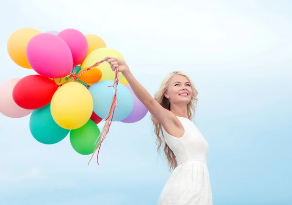 Lachende vrouw met kleurrijke ballonnen buiten — Stockfoto