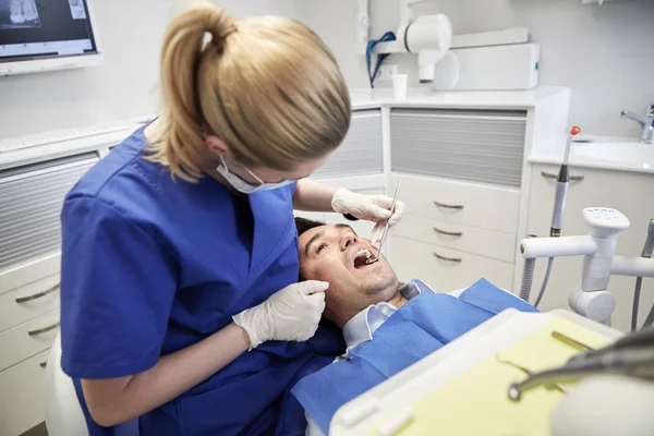 Θηλυκό οδοντίατρο που ελέγχου επάνω αρσενικά δόντια ασθενών — Φωτογραφία Αρχείου