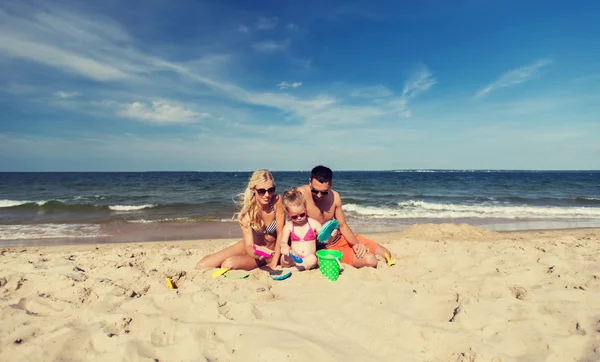 Famiglia felice giocare con i giocattoli di sabbia sulla spiaggia — Foto Stock