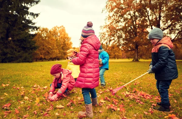 Grupo de niños recogiendo hojas en el parque de otoño — Foto de Stock