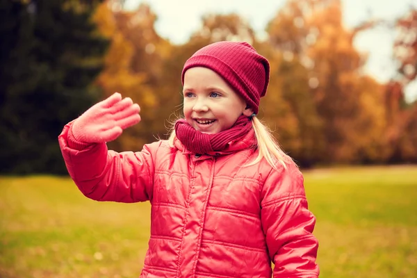 Щаслива маленька дівчинка махає рукою в осінньому парку — стокове фото