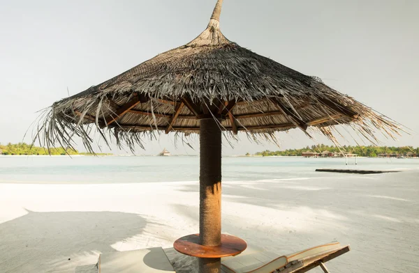 Palapa e espreguiçadeiras por mar na praia das maldivas — Fotografia de Stock