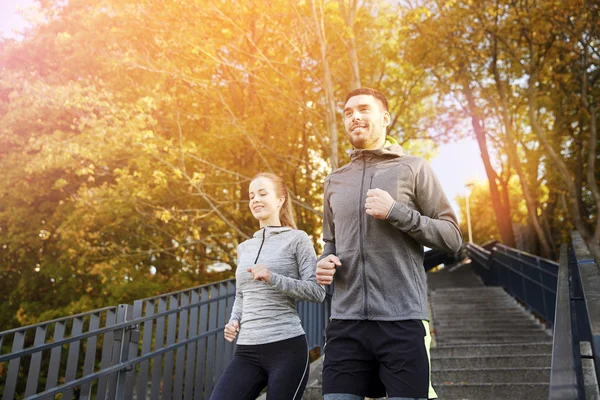 Happy couple running downstairs in city — Stock Photo, Image