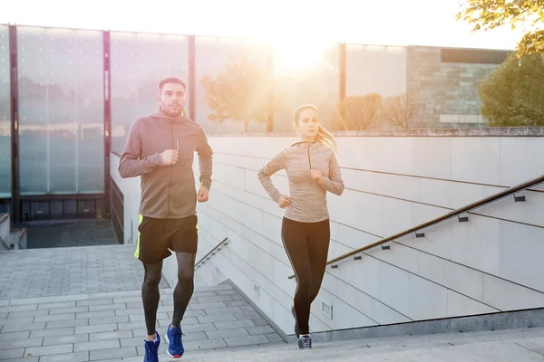 Happy couple running upstairs on city stairs — Stock Photo, Image