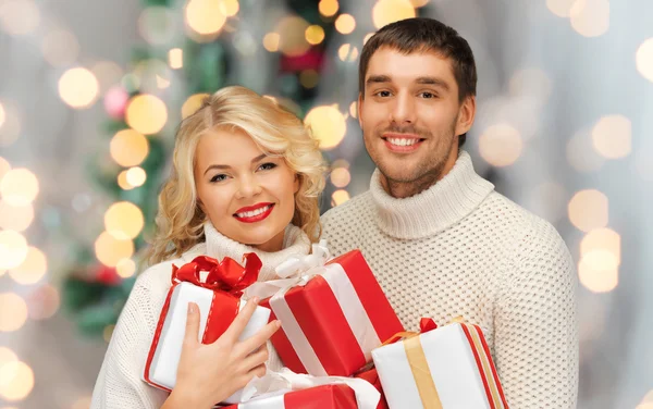 Heureux couple en chandails tenant des cadeaux de Noël — Photo