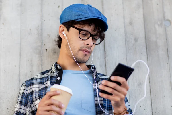 Man med hörlurar och smartphone dricka kaffe — Stockfoto