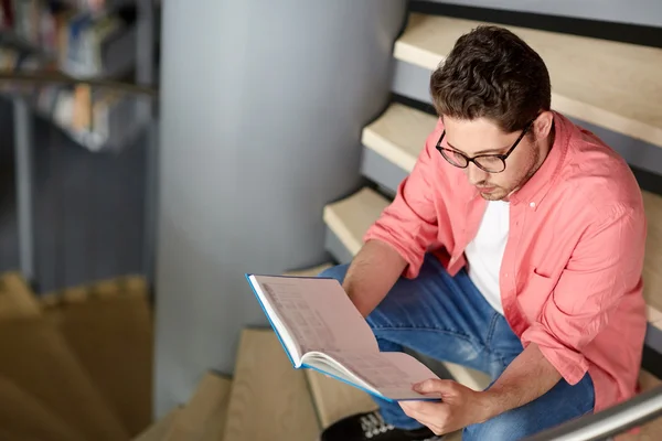 Studente ragazzo o giovane lettura libro in biblioteca — Foto Stock