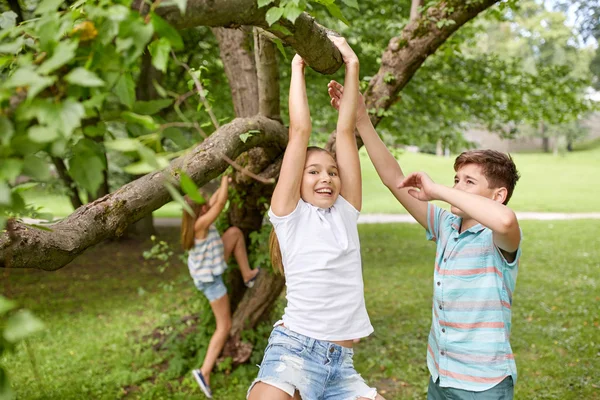 Szczęśliwy kids wiszące na drzewie w parku lato Zdjęcia Stockowe bez tantiem