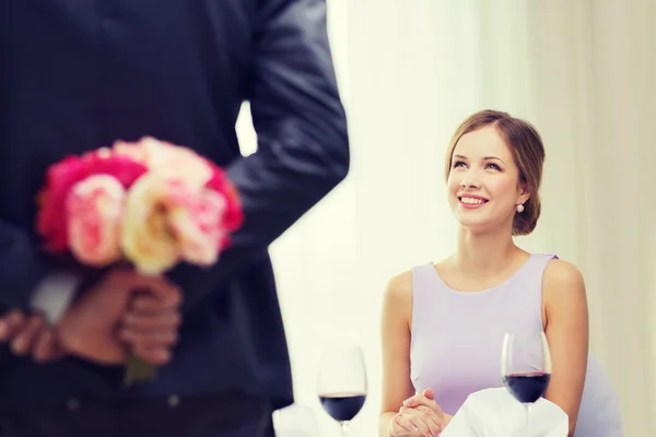 Junge Frau blickt Mann mit Blumenstrauß an — Stockfoto