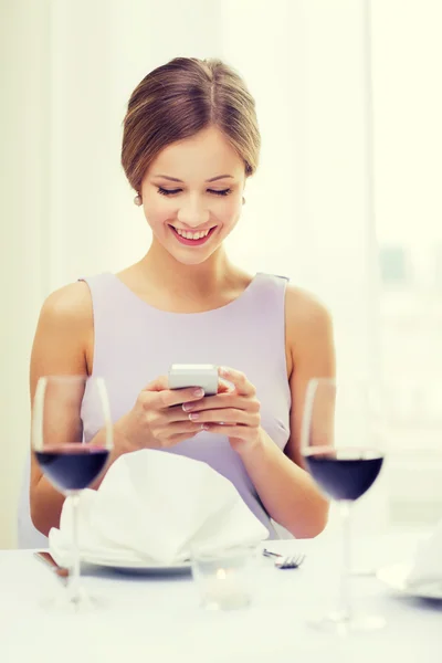 Smiling woman with smartphone at resturant — Stock Photo, Image