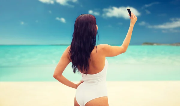 Young woman taking selfie with smartphone on beach — Stock Photo, Image
