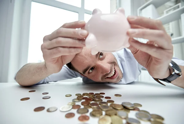 Businessman with piggy bank and coins at office Royalty Free Stock Photos