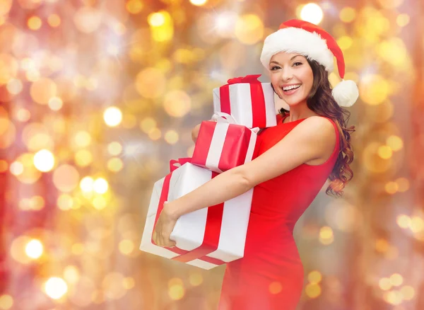 Smiling woman in santa hat holding gift boxes — Stock Photo, Image