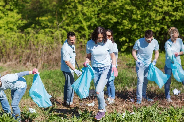 Wolontariusze z workami na śmieci sprzątający teren parku — Zdjęcie stockowe