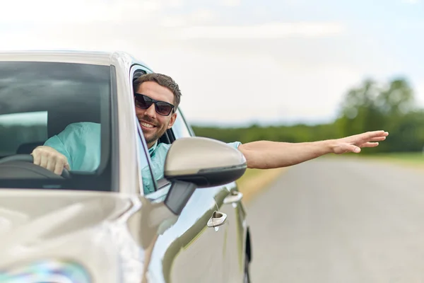 Hombre feliz en tonos coche de conducción y la mano ondulante — Foto de Stock