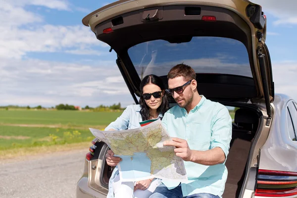 Homem feliz e mulher com mapa da estrada no carro hatchback — Fotografia de Stock