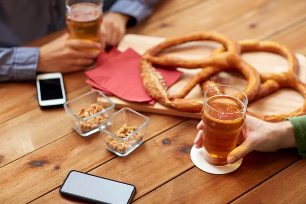 Närbild av händer med smartphones och öl på bar — Stockfoto