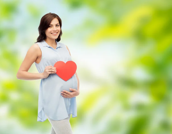 Glückliche schwangere Frau mit rotem Herz, das den Bauch berührt — Stockfoto