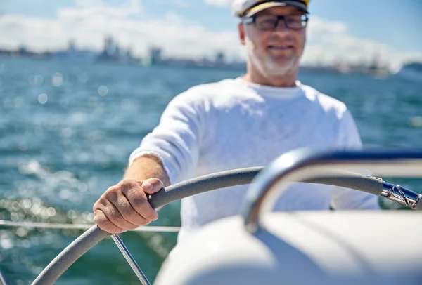 Homem sênior no leme em barco ou iate navegando no mar — Fotografia de Stock