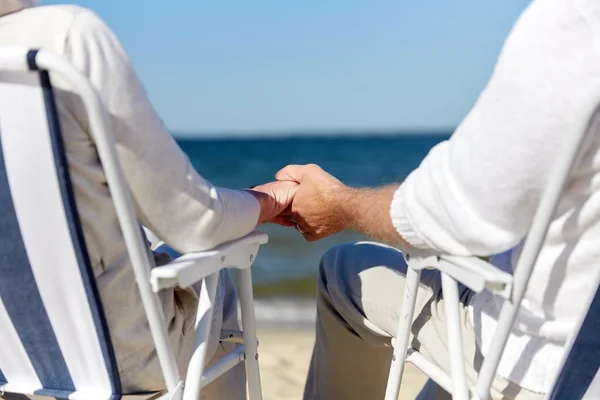 Пожилая пара, сидящая на стульях на пляже — стоковое фото