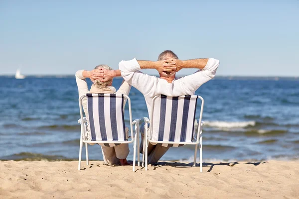 Старша пара сидить на стільцях на літньому пляжі — стокове фото
